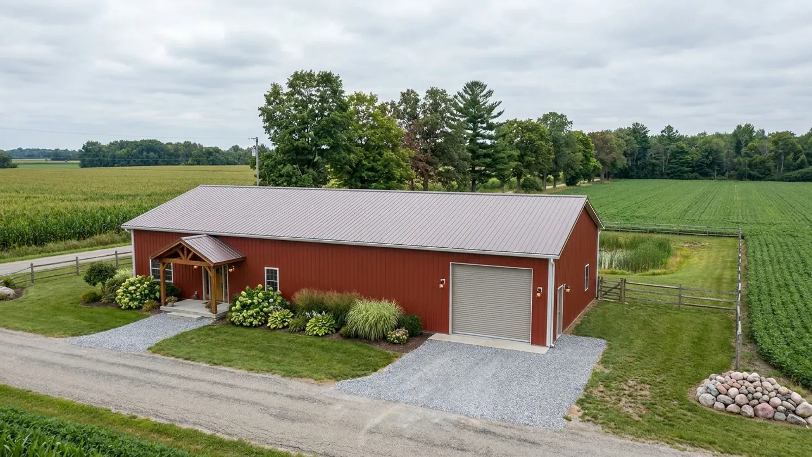 A completed 40x60 barndominium in barn red, showing a residential entry on one end and a wide shop door on the other under one continuous roof.